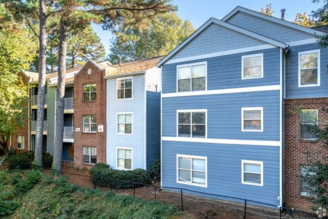 A blue building with white windows is situated next to a green building with red brick.